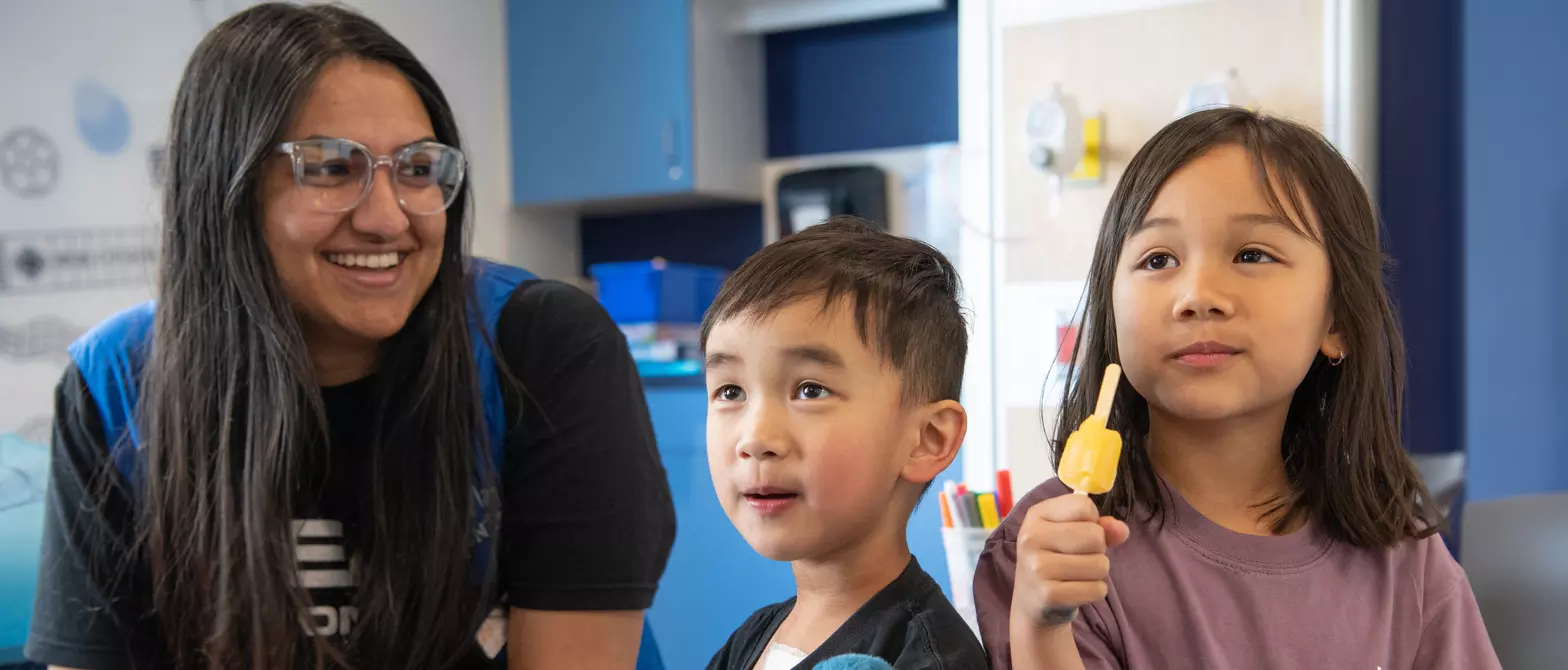two siblings with volunteer eating popsicle