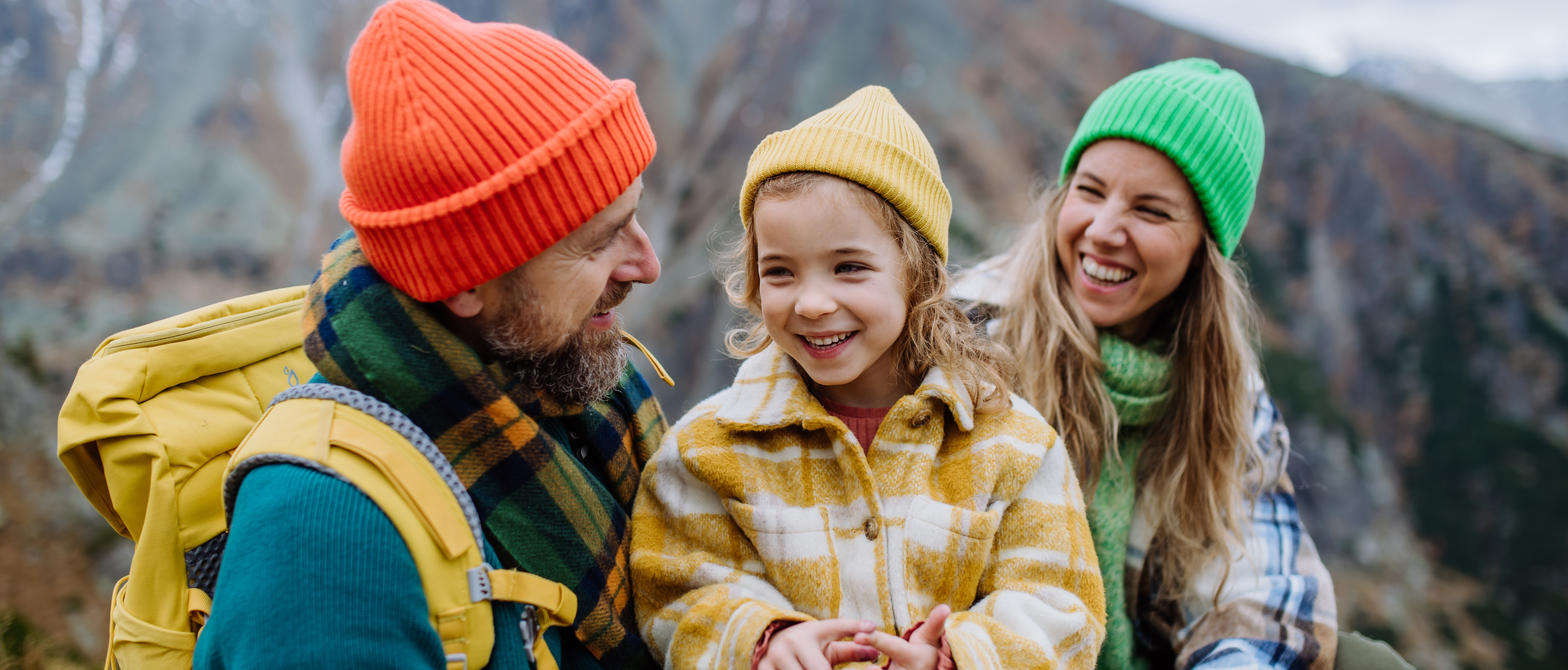 A family laughs while stopping at the summit of a mountain