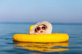 Baby in sunhat and sunglasses swimming with floatie
