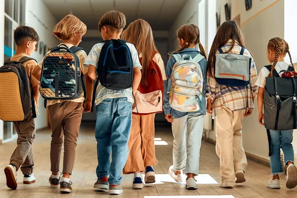 Children with backpacks walking in the hallway at school
